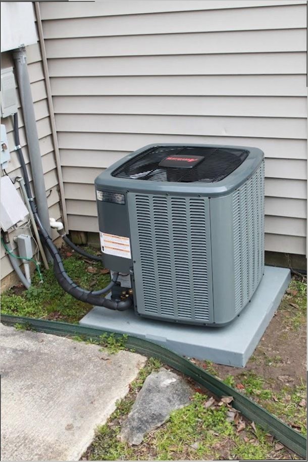 Newly installed residential air conditioning condenser unit against a home's siding